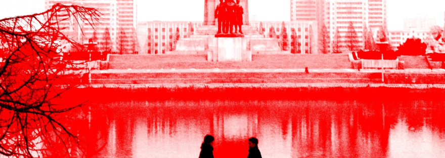 A false-colour photograph of two people talking in front of the Juche Tower in Pyongyang, North Korea.